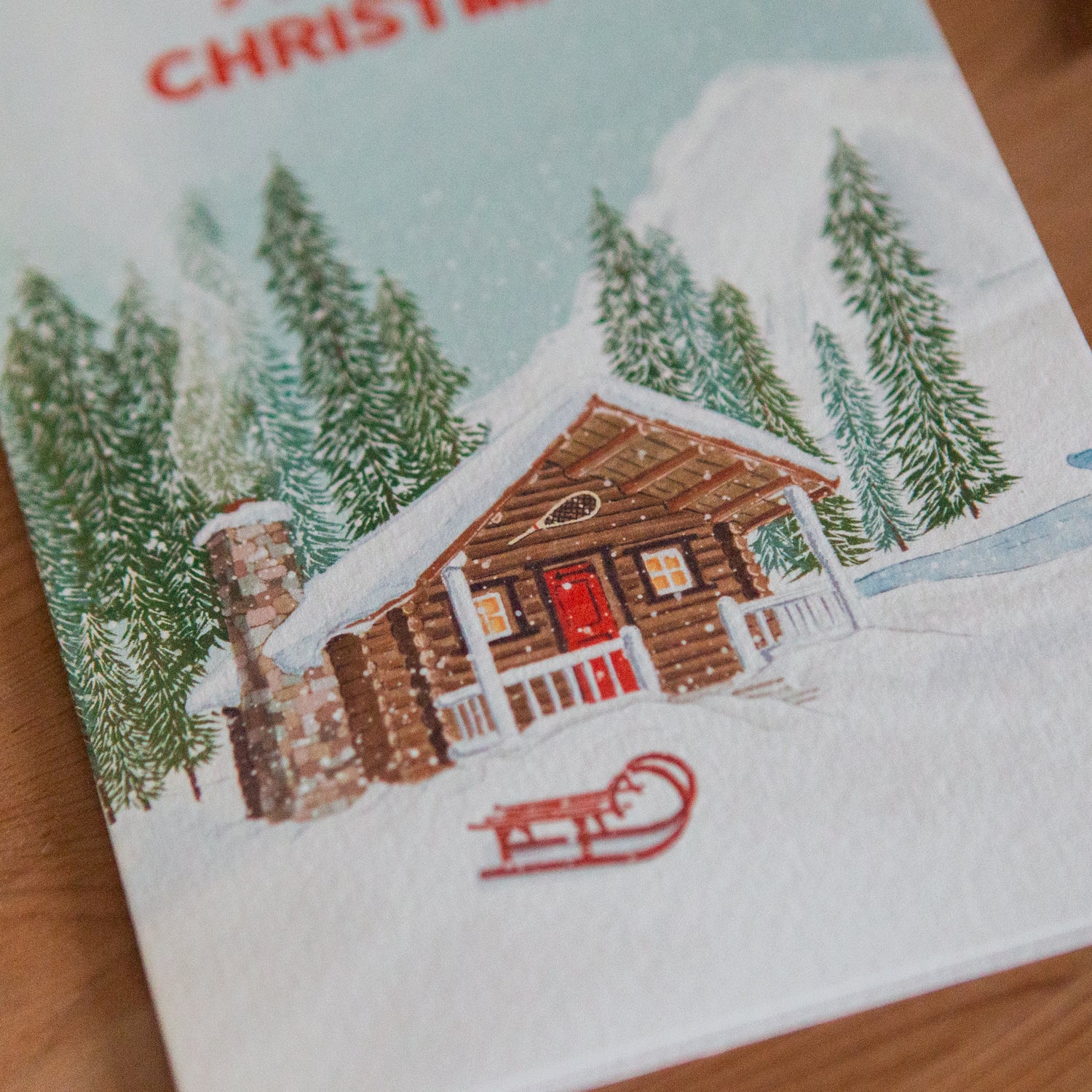 Card with a Christmas design featuring a log cabin and trees