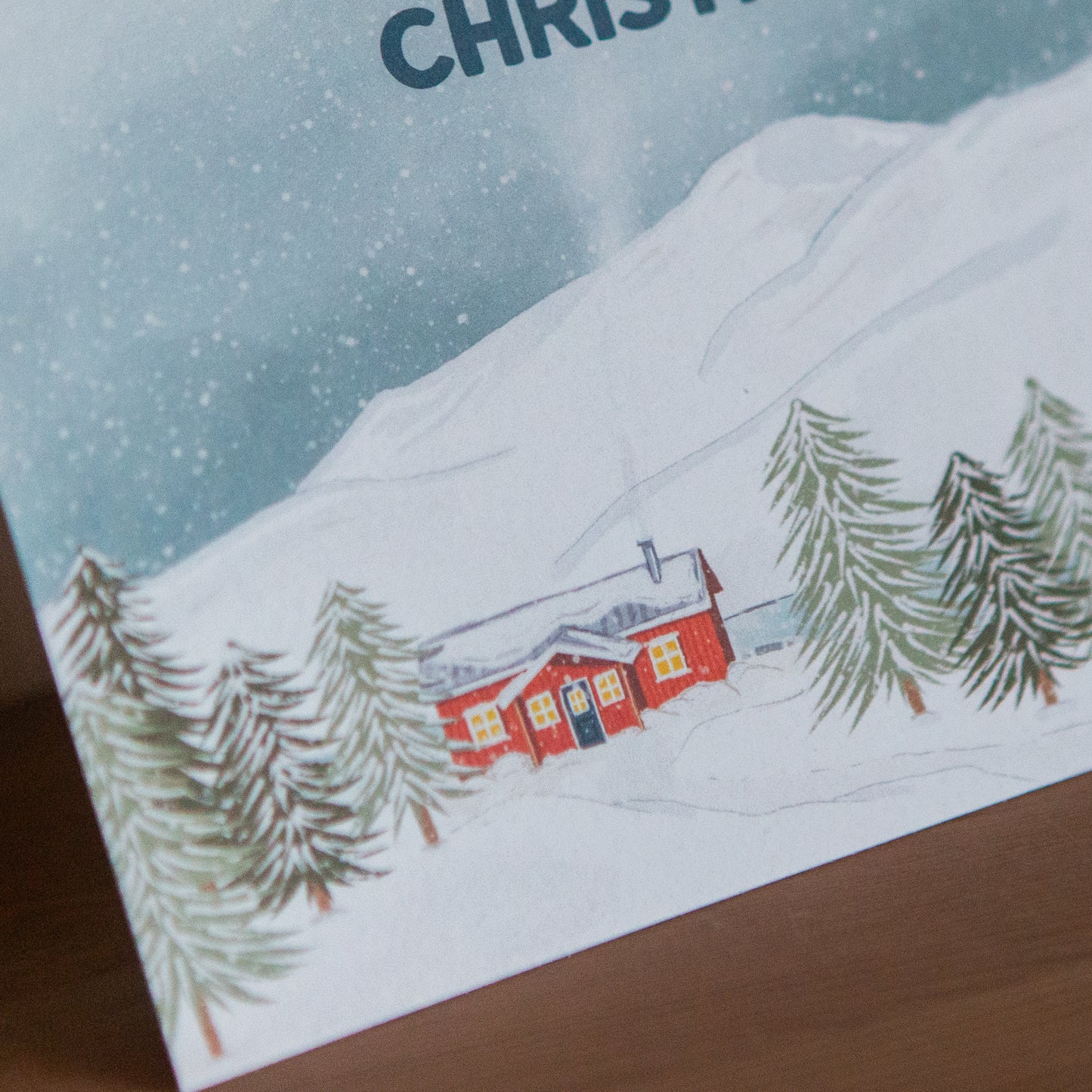 Christmas card with a snowy landscape and red cabin