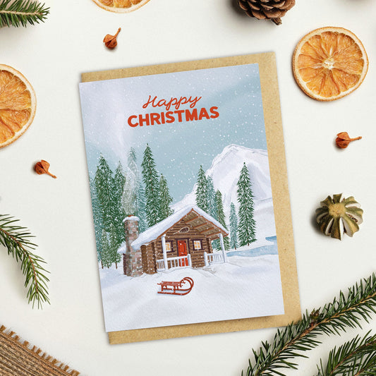 Christmas card with a snowy Canadian cabin illustration surrounded by festive decorations on a white background